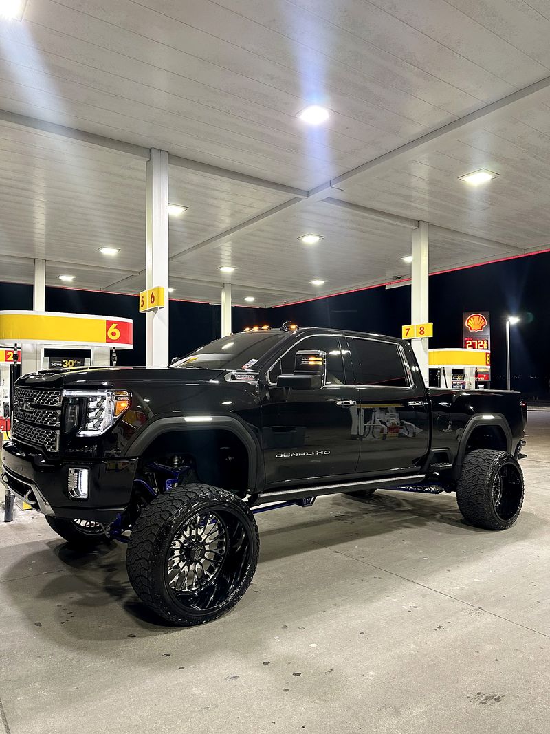 Black GMC Denali HD with mirror-gloss paint under gas station lights