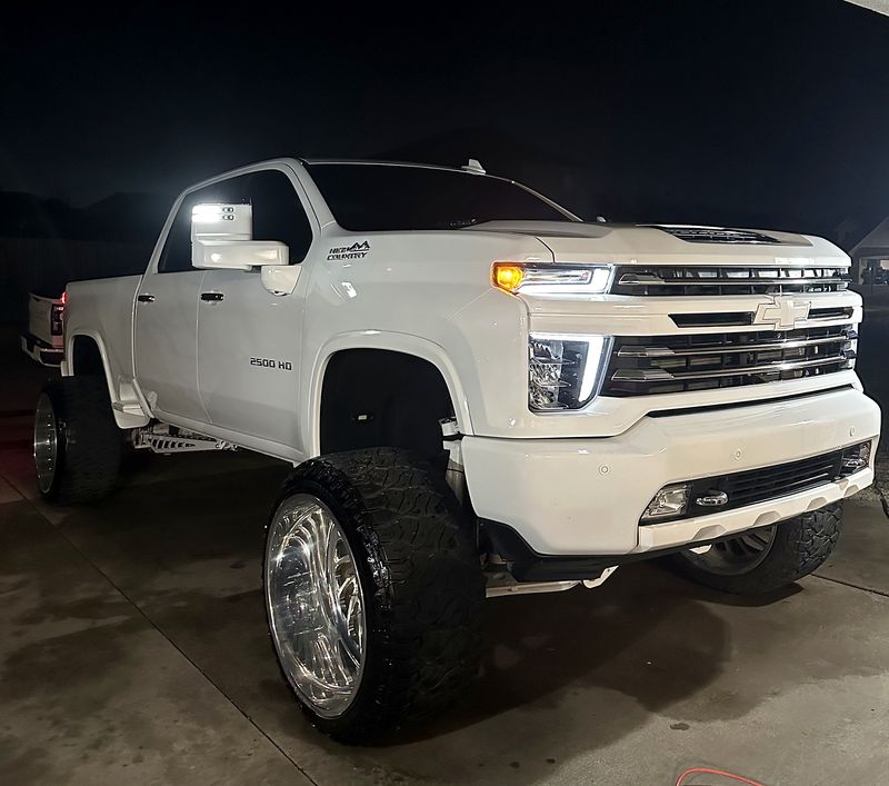 White Chevy Silverado HD with polished wheels at night
