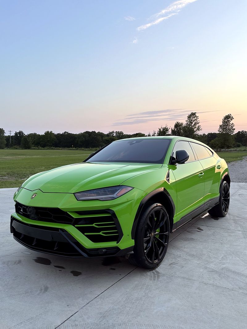 Green Lamborghini Urus with glossy paint at sunset